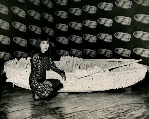 Яеи Кусама на фоне инсталляции «Накопление: шоу тысячи лодок», 1965 год